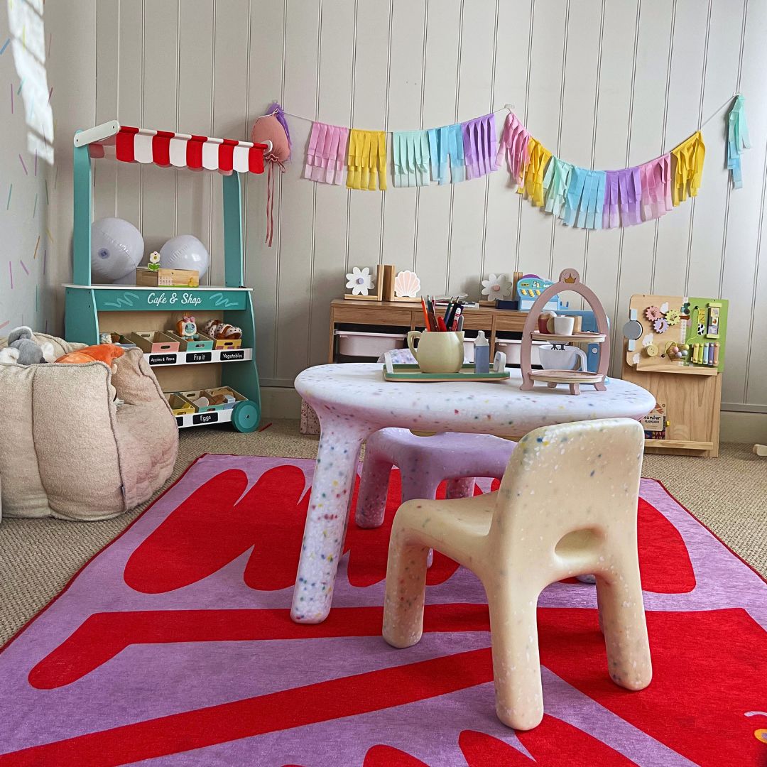 Children's playroom with a small table and chair set on a colorful rug.