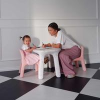 Woman and child sitting at a small table on a checkered floor, engaged in an activity.
