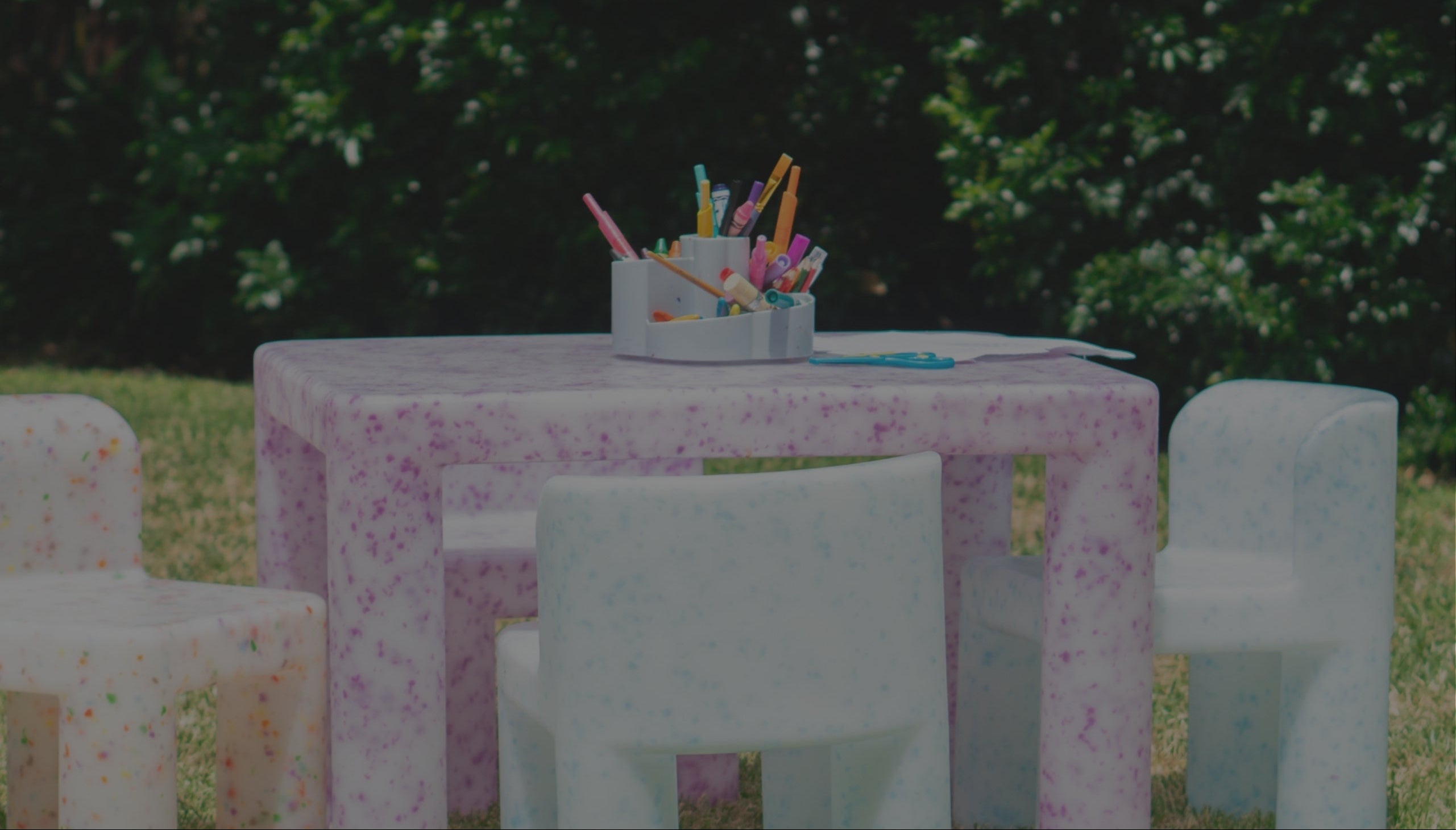 Children's table and chairs set with a floral tablecloth outdoors.